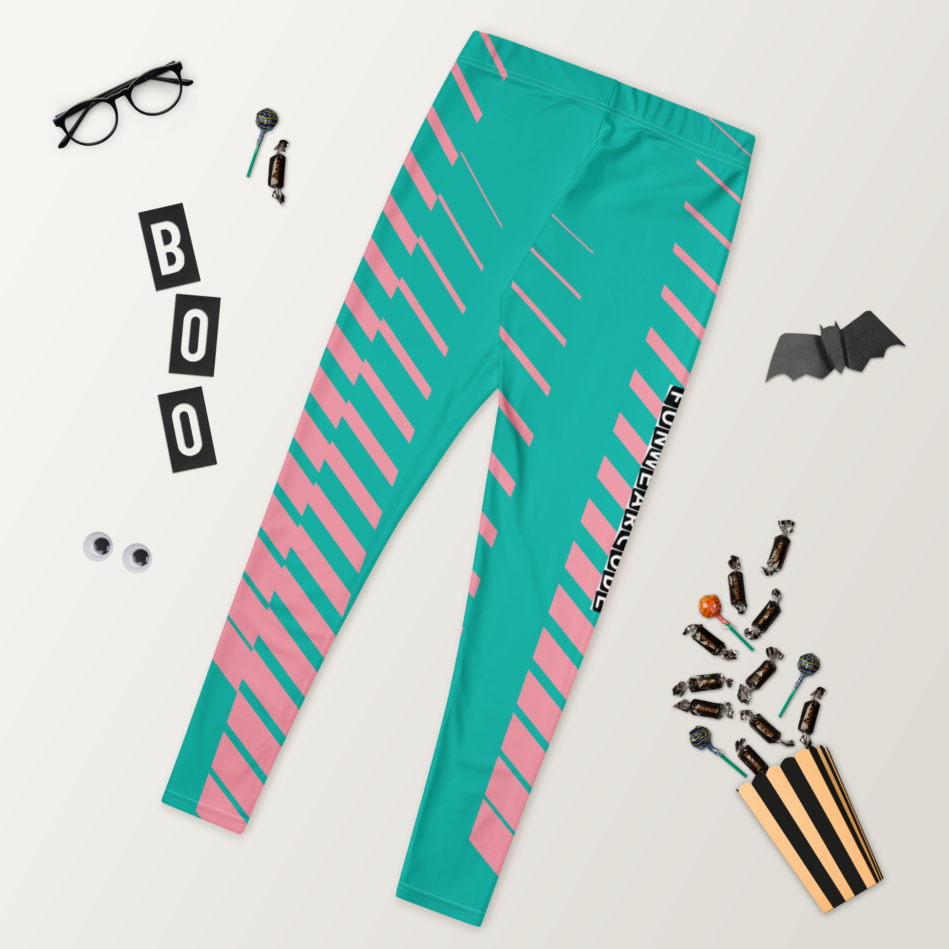 Teal leggings with pink stripes on a white background with Halloween decorations.