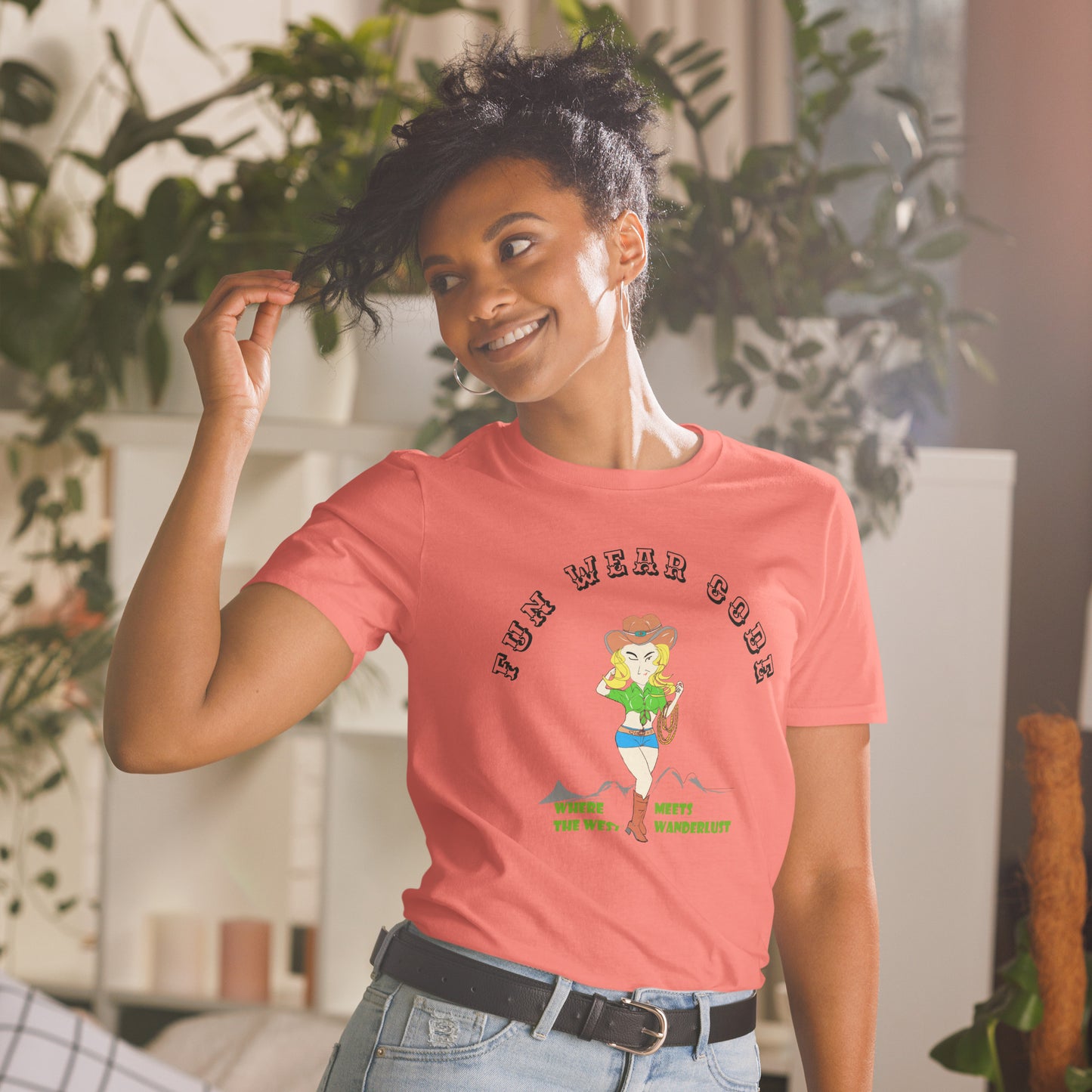 Woman wearing a pink t-shirt with a graphic design of a cowgirl and text " FUN WEAR CODE" in a room with plants