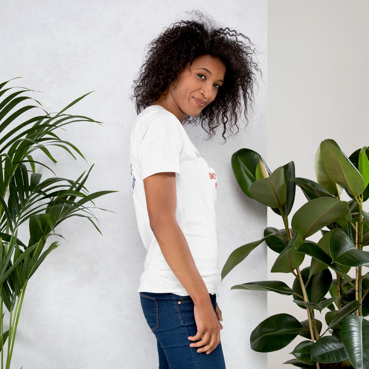 Woman wearing a white t-shirt with a 'Fun Wear Code' text logo and colorful texts, standing between two potted plants against a light gray wall.