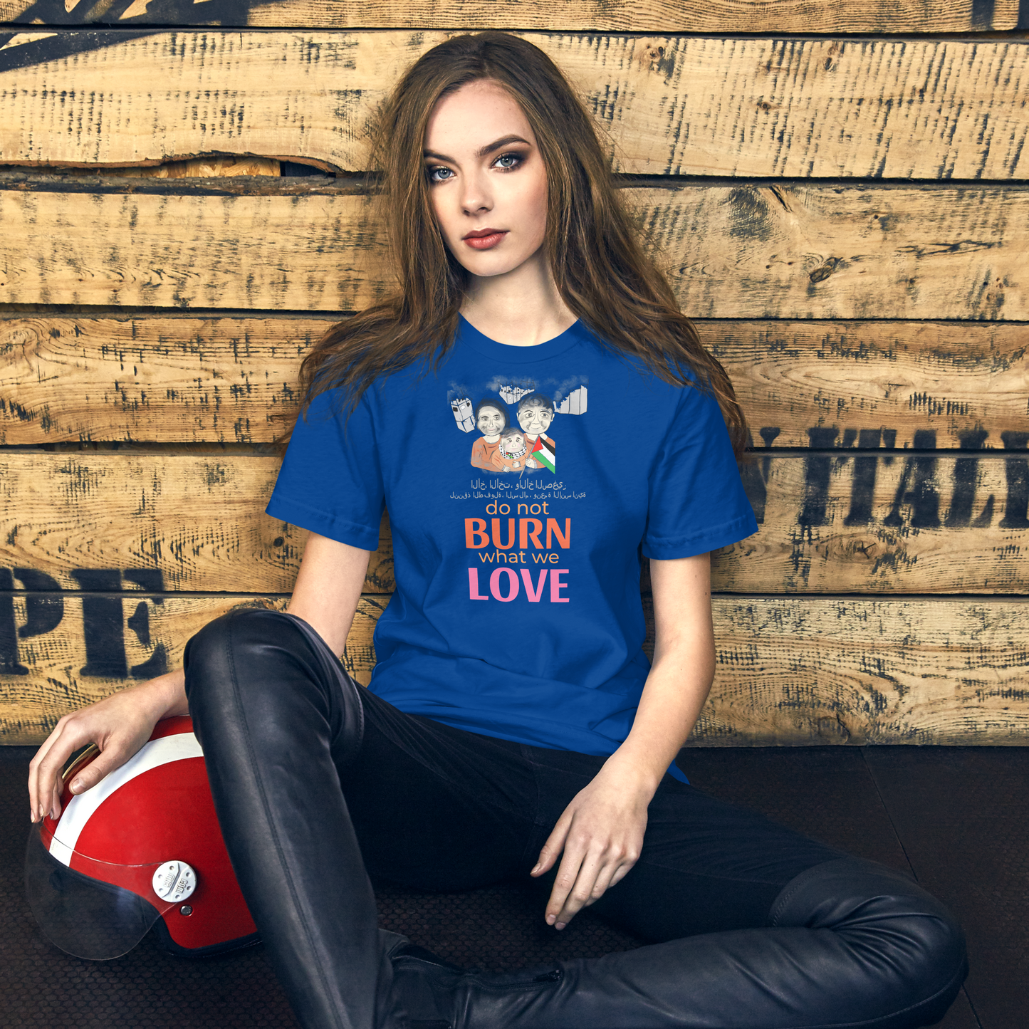 Woman wearing a blue t-shirt with a printed design, sitting against a wooden wall.